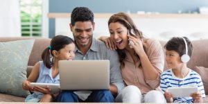 parents-kids-using-laptop-digital-tablet-living-room-min